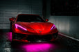 Red Corvette in a garage with pink headlight DRLs.
