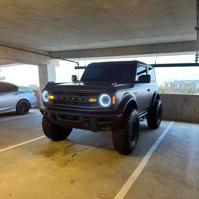 Two Ford Broncos on a rooftop parking lot, both equipped with Oculus Headlights.