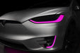 Close-up on the headlights and fog lights of a Tesla Model X with pink DRLs.
