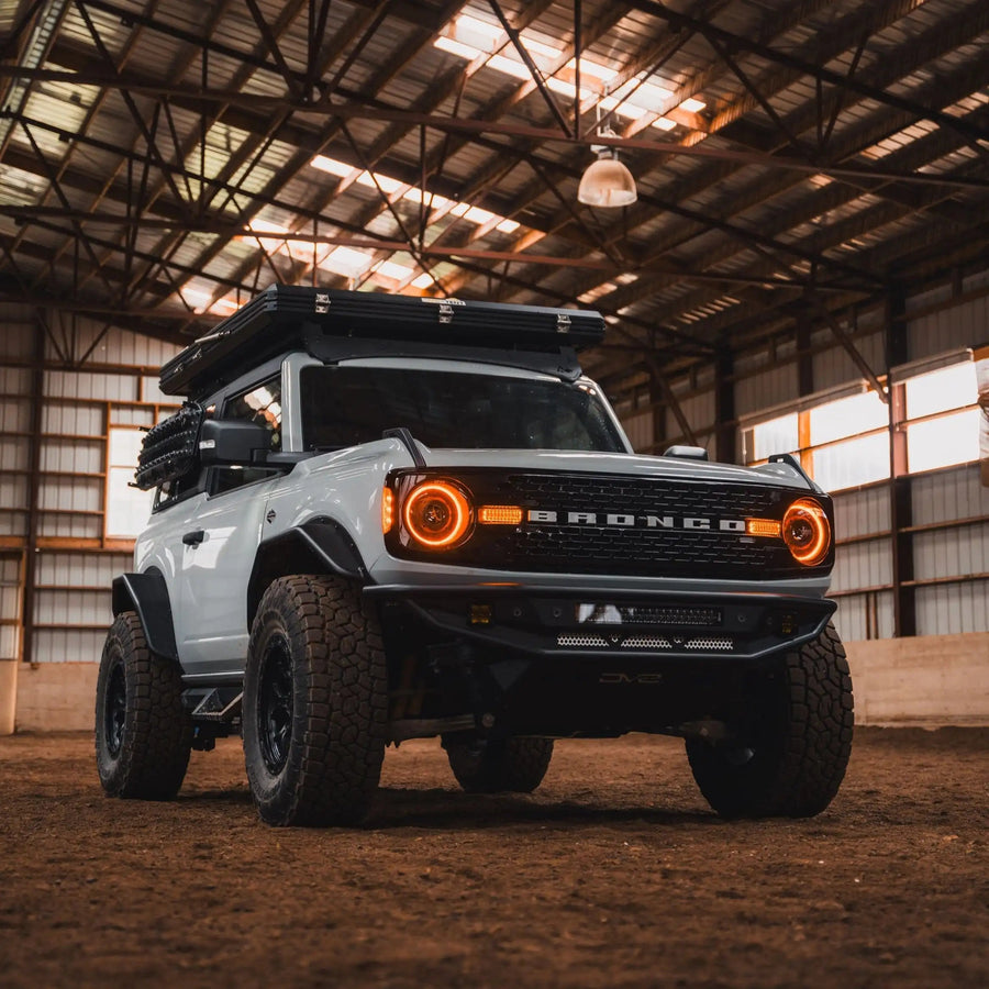 White Ford Bronco riding on a sunset trail, with amber Oculus Headlights turned on.