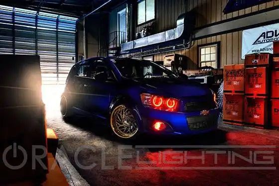 Three quarters view of a Chevrolet Sonic with red LED headlight and fog light halo rings installed.