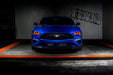 Straight front view of a blue Ford Mustang with red LED headlights.