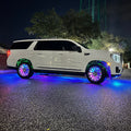 Side view of a GMC Denali with rainbow LEDs shining through the wheel wells.