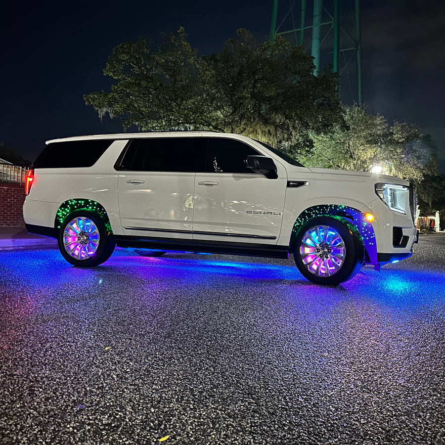 Side view of a GMC Denali with rainbow LEDs shining through the wheel wells.