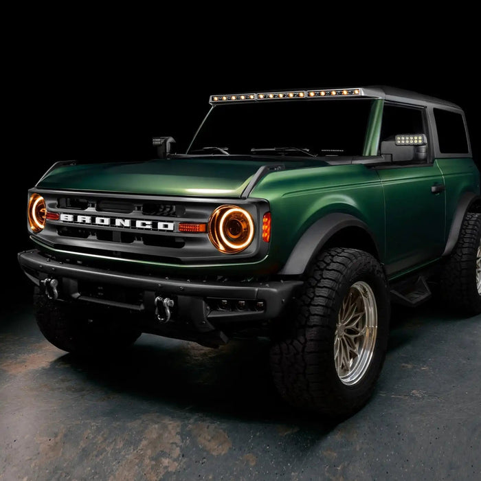 Three quarters view of a green Ford Bronco with multiple ORACLE Lighting products installed, including the Integrated Windshield Roof LED Light Bar System.
