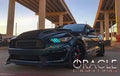 Three quarters view of a Ford Mustang with green headlight DRLs.