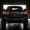 Black Toyota truck with illuminated headlights in a dark setting