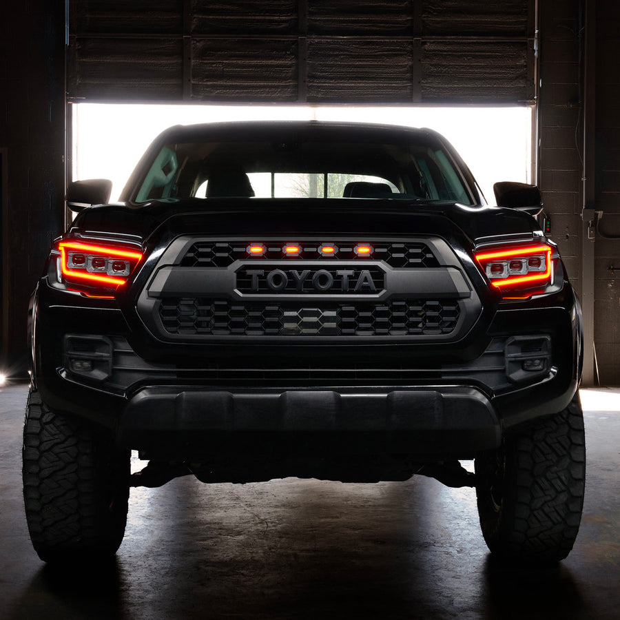 Black Toyota truck with illuminated headlights in a dark setting