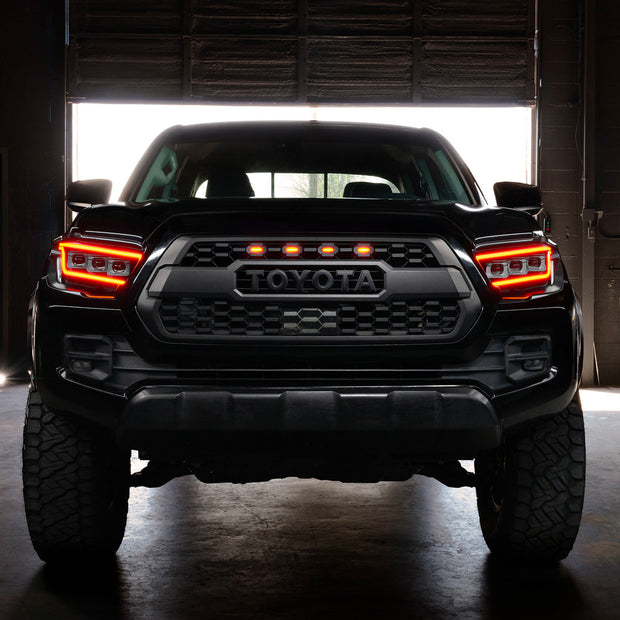Black Toyota truck with illuminated headlights in a dark setting