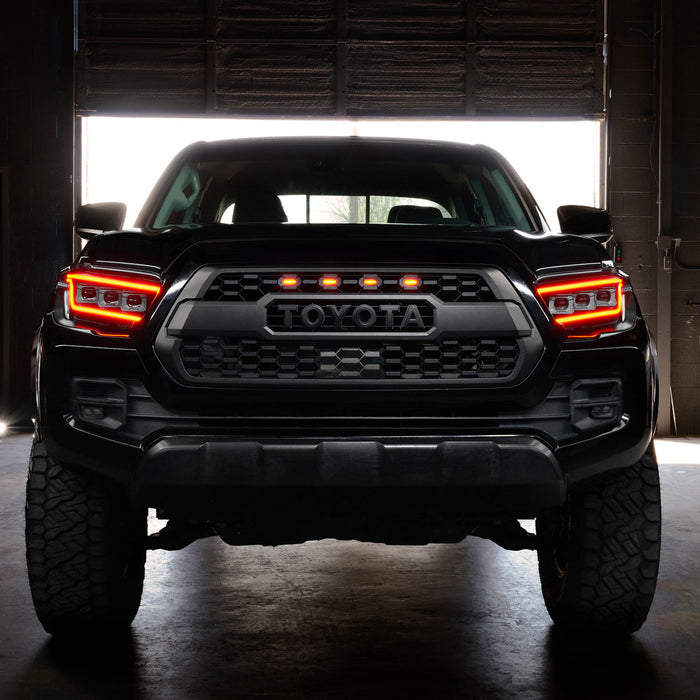 Black Toyota truck with illuminated headlights in a dark setting