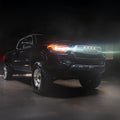 Black Toyota truck with glowing headlights on a dark background