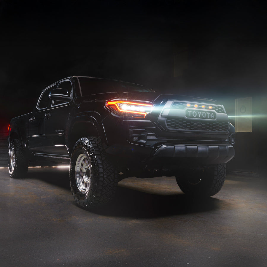 Black Toyota truck with glowing headlights on a dark background