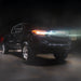 Black Toyota truck with glowing headlights on a dark background