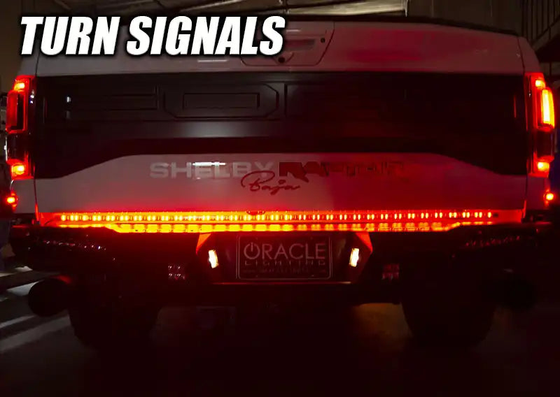 Rear view of a Ford Raptor with 60” Double Row LED Truck Tailgate Light Bar installed and turn signal on.