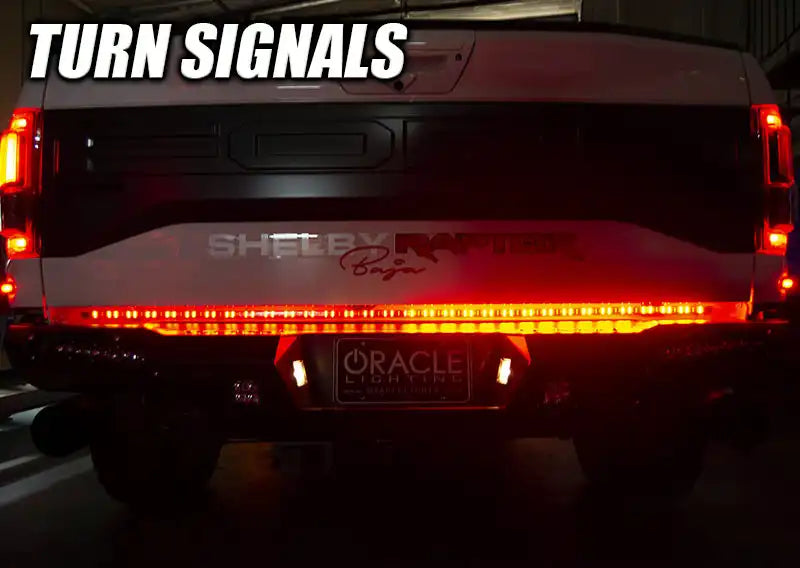 Rear view of a Ford Raptor with 60" Double Row LED Truck Tailgate Light Bar installed and turn signal on.
