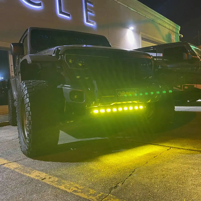 Front view of a Jeep Wrangler in a parking lot, with LED Integrated Skid Plate turned on, shining yellow LEDs.