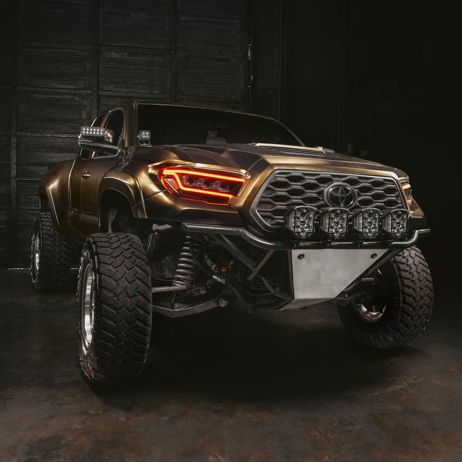 Bronze Toyota truck with large off-road tires in a dark setting