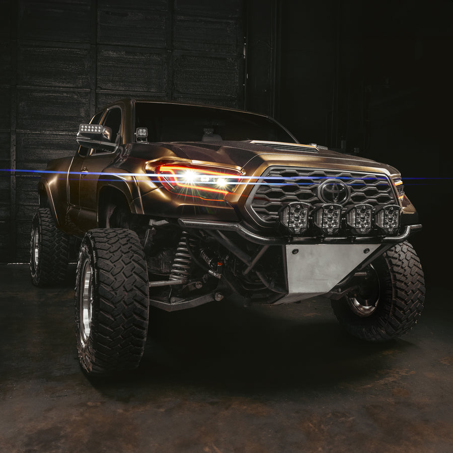Toyota truck with illuminated headlights in a dark setting