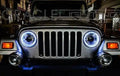 Front end of a Jeep with white LED headlight halo rings installed.