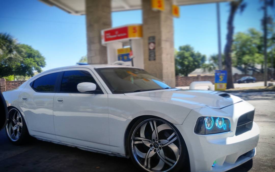 White charger at a gas station with blue halo headlights