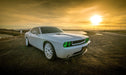 Three quarters view of a white Dodge Challenger with green LED headlight and fog light halo rings installed.