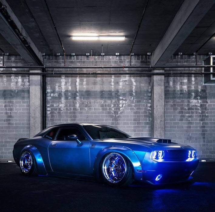 Three quarters view of a blue Dodge Challenger with blue LED headlight and fog light halo rings installed.