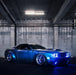 Three quarters view of a blue Dodge Challenger with blue LED headlight and fog light halo rings installed.
