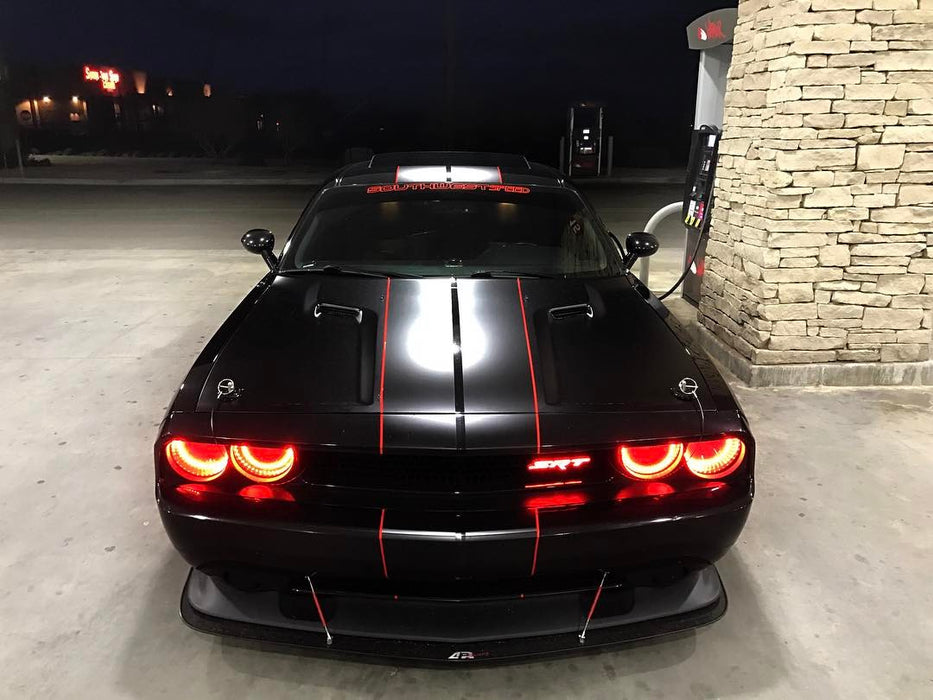 Front view of a black Dodge Challenger with red LED headlight halo rings installed.