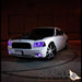 Three quarters view of a white Dodge Charger with purple LED headlight and fog light halo rings installed.