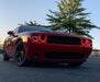Three quarters view of a red Dodge Challenger with red LED headlight halo rings installed.