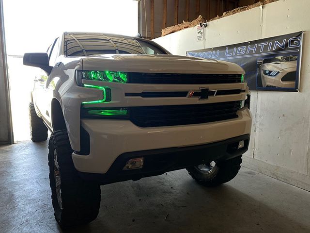 White Chevrolet Silverado with green demon eye projectors and DRLs.