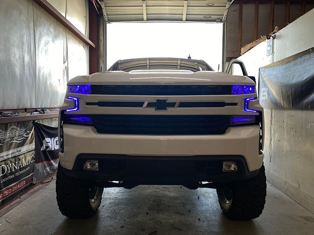 White Chevrolet Silverado with blue demon eye projectors and DRLs.