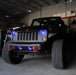 Front end of a Jeep Wrangler JK with blue LED headlight and fog light halos installed.