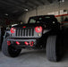 Front end of a Jeep Wrangler JK with red LED headlight and fog light halos installed.