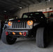 Front end of a Jeep Wrangler JK with amber LED headlight and fog light halos installed.