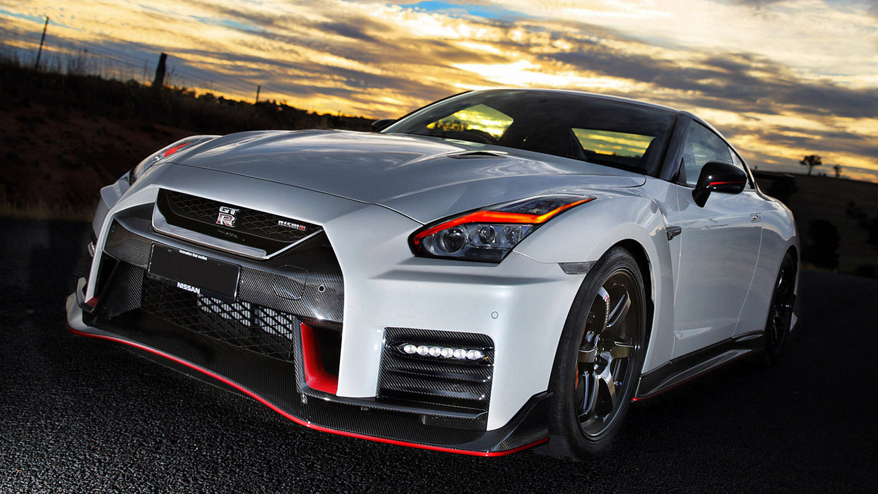 Three quarters view of a white Nissan GT-R with red headlight DRLs.