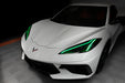 Front end of a white C8 Corvette with green headlight DRLs.