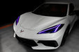 Front end of a white C8 Corvette with purple headlight DRLs.