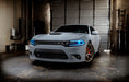 Three quarters view of a grey Dodge Charger with cyan headlight DRLs.