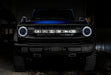 Front view of a blue Ford Bronco with white headlight halos.