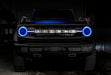 Front view of a blue Ford Bronco with blue halos and DRLs.