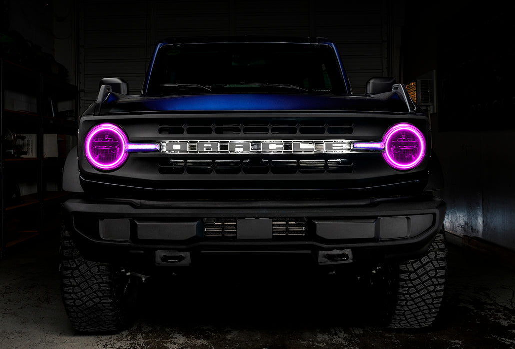 Front view of a blue Ford Bronco with pink halos and DRLs.
