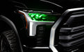 Close-up of a 2022+ Toyota Tundra headlight module installed with green demon eye projector.