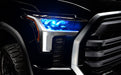 Close-up of a 2022+ Toyota Tundra headlight module installed with cyan demon eye projector.