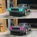 Three quarters view of a grey Dodge Challenger with green and pink LED headlight halo rings installed.