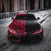 Front view of a wrapped Toyota Supra with red headlight DRLs.