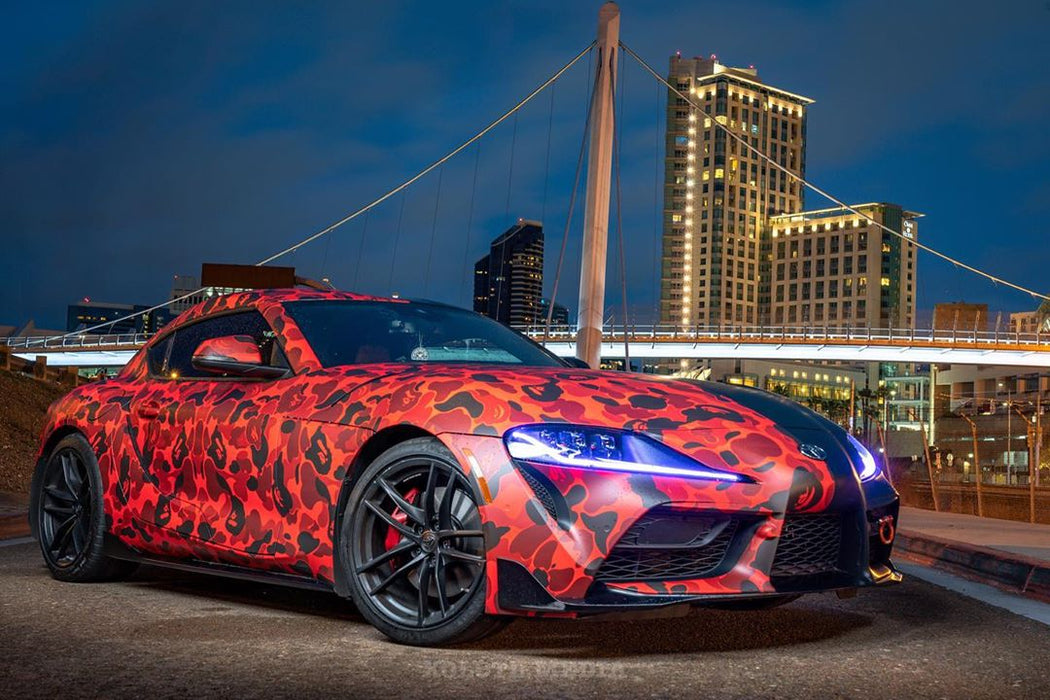 Three quarters view of a wrapped Toyota Supra with blue headlight DRLs.