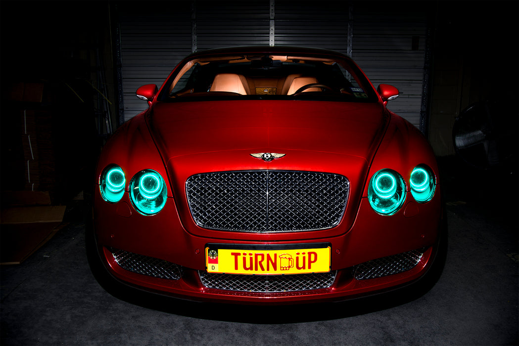 Front view of a Bentley Continental GT with aqua LED headlight halo rings installed.