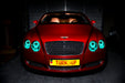 Front view of a Bentley Continental GT with aqua LED headlight halo rings installed.