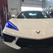 Close-up on the front end of a white C8 Corvette with blue headlight DRLs.